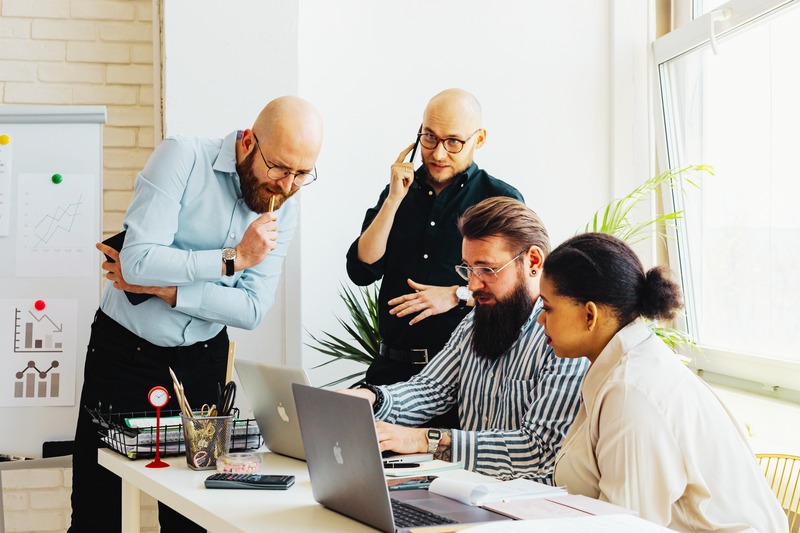 Vier Personen besprechen gemeinsam einen digitalen Arbeitsprozess